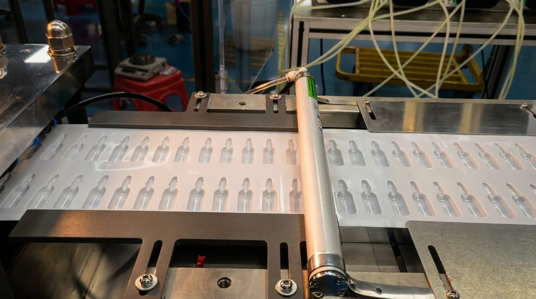 A web of formed film cavities passing under the sealing roller